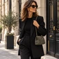 Preview: Vimoda Aura Clutch in Oliv an goldfarbener Kette zu schwarzem Outfit getragen, Modell und Hintergrund mit KI erstellt