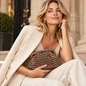 Preview: Vimoda CLAUDINE Bronze als Clutch zu einem hellen eleganten Outfit getragen, KI-Visualisierung