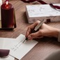 Preview: Caran d'Ache Léman Toile de Jouy Bordeaux Kugelschreiber beim Schreiben einer Karte