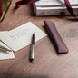 Preview: Caran d'Ache Léman Bordeaux Kugelschreiber und Lederetui auf modernem Schreibtisch