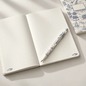 Preview: Caran d'Ache Toile de Jouy A5 notebook open with white 849 ballpoint pen