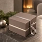Preview: Embacollage MOKKA Geschenkbox mit silberfarbenem Geschenkband, weihnachtlich inszeniert mit Tannenzweig und silberner Christbaumkugel