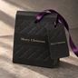 Preview: Schwarzer Embacollage DIAMANT 3D Geschenkanhänger an passender Merry Christmas Geschenktasche mit Rautenprägung und goldener Schrift, dekoriert mit violettem Band