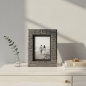 Preview: Lionetti Bilderrahmen Francesco anthrazit Croco-Leder auf Travertin-Sideboard mit Schwarzweiß-Foto eines Paares am Strand
