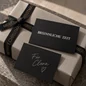 Preview: Schwarze Mini-Weihnachtskarte Besinnliche Zeit mit Beschriftungsbeispiel Für Clara auf einem weihnachtlichen Geschenk