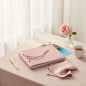Preview: Trixi Gronau CALLA A5 photo album dusty rose pink Dollaro pebble grain leather with leather cord binding, pasted travel photographs peeking out from behind on blush linen with garden rose, rosé champagne, gold pen and rose silk handkerchief in airy boudoi
