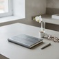 Preview: Trixi Gronau ISOLA photo album 23x30 silver-grey mamba snake leather on pale concrete with espresso, white orchid and round tortoiseshell glasses in modern minimalist study