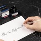 Preview: Schriftzug Bleu des Profondeurs auf weißem Papier neben Tintenflakon und Verpackung