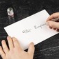 Preview: Hand schreibt Vert Empire mit einer Glasfeder auf weißes Papier, daneben Jacques Herbin Aluminiumdose