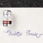 Preview: Jacques Herbin Violette Pensée Aluminiumdose neben violettem Kalligrafie-Schriftzug auf Papier
