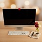 Preview: Trixi Gronau ANTISPY Webcam Cover L in leuchtendem Rot aus feinem Leder, auf einem Apple iMac am oberen Bildschirmrand angebracht. Auf einem hellen Eichen-Schreibtisch mit Apple-Tastatur, kleiner Vase mit roten Ranunkeln und cremefarbenen Rosen, schwarzem