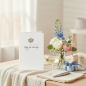 Preview: Trixi Gronau KING FOR THE DAY greeting card, B6 portrait in white paper with a small antique gold crown centered on the upper third, and below it in flowing royal-blue handwritten script the phrase King for the day. On a light oak desk with a small vase o