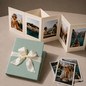 Preview: Trixi Gronau NELLI Galluchat Mint photo leporello, small accordion album unfolded with five summer travel photos: blonde woman at the pool, white Mediterranean village, couple at a cafe, blonde woman in a boat, mountain landscape. Beside it the closed alb