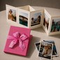 Preview: Trixi Gronau NELLI Galluchat Pink photo leporello, small accordion album unfolded with five travel photos. Beside it the closed album in pink galluchat embossing, wrapped with a delicate pink satin ribbon. Three additional polaroid photos. On a light crea