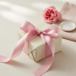 Preview: Vivant Geschenkband SATIN rosa (25 mm) als zarte Schleife auf cremefarbenem Geschenk, mit frischer Gartenrose auf weichem Leinen. Romantische feminine Verpackung. Trixi Gronau Concept Store, Hamburg-Lokstedt.