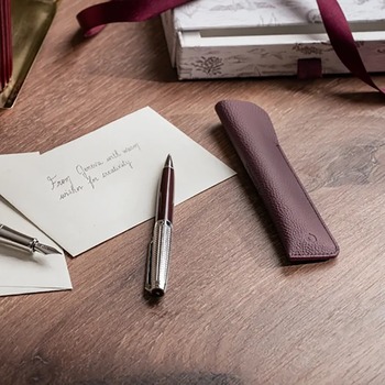 Preview: Caran d'Ache Léman Bordeaux Kugelschreiber und Lederetui auf modernem Schreibtisch