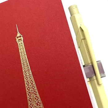 Detail des gelben Schreibgeräts und des Filofax Norfolk Magnetic Clip neben goldenem Eiffelturm auf rotem Notizbuch