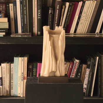 House by® limitierte Kerze by Michele Lamy Object No001, auf dem Sockel vor Buechern