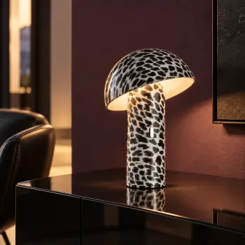 Preview: Sompex SVAMP LEOPARD rechargeable LED table lamp with black-and-white leopard print, glowing warmly on a dark sideboard