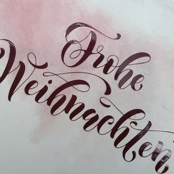 Preview: Detail der weinroten Kalligrafie mit glänzendem Lackdruck auf der TRIXI GRONAU Weihnachtskarte Frohe Weihnachten