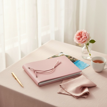 Preview: Trixi Gronau CALLA Fotoalbum A5 rosa Dollaro Genarbung mit Lederkordel-Bindung, eingeklebte Reise-Fotos schauen hinten heraus auf blush Leinen mit Gartenrose, Rosé, Goldstift und rosa Seidentuch im hellen Boudoir