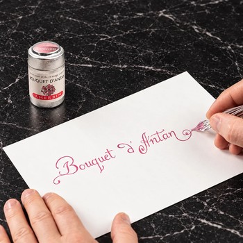 Preview: Schräg fotografierter Schriftzug Bouquet d’Antan in rosafarbener Tinte auf hellem Papier