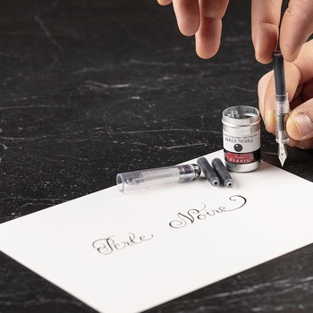 Tintenpatrone Perle Noire wird in einen Füllhalter eingesetzt, daneben die geöffnete Aluminiumdose