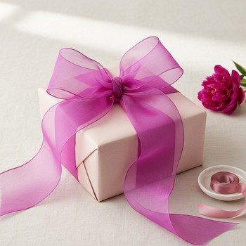 Preview: Vivant ORGANZA WOVEN ribbon in vibrant magenta (70 mm wide) tied as a voluminous sheer bow on a blush-wrapped gift, with a fuchsia peony on warm white linen. Festive feminine wrapping. Trixi Gronau Concept Store, Hamburg.