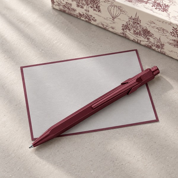 Caran d'Ache 849 Toile de Jouy Burgundy with grey Crown Mill correspondence card and gift box, background AI visualisation