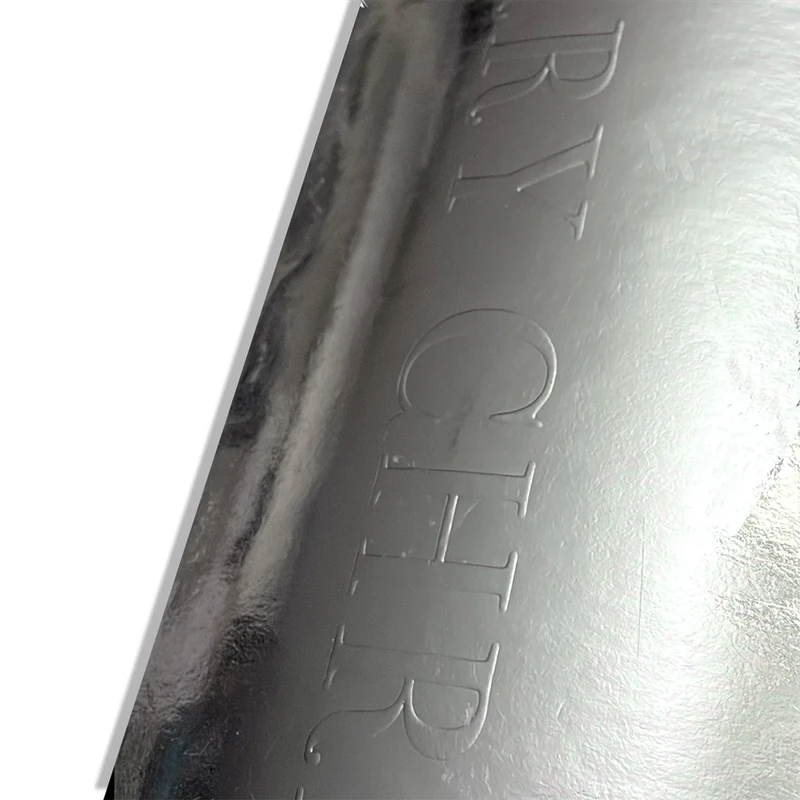 Nahaufnahme der MERRY CHRISTMAS Blindprägung auf der spiegelnden Silbermetallic-Oberfläche des Embacollage SILVIO Aufklebers