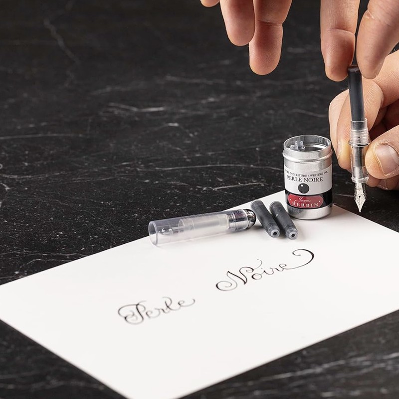 Tintenpatrone Perle Noire wird in einen Füllhalter eingesetzt, daneben die geöffnete Aluminiumdose