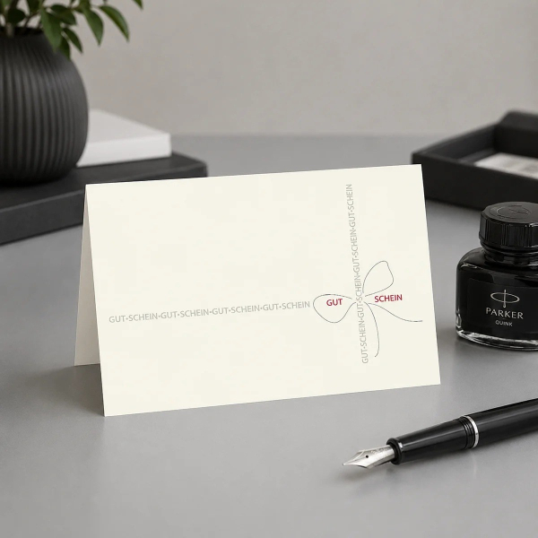 Trixi Gronau LOOP voucher card, B6 landscape in cream pearlescent paper with an artistic bow composition made from the typographically repeated phrase GUT-SCHEIN in fine grey sans-serif, the central GUT and SCHEIN highlighted in deep wine red. On a light 