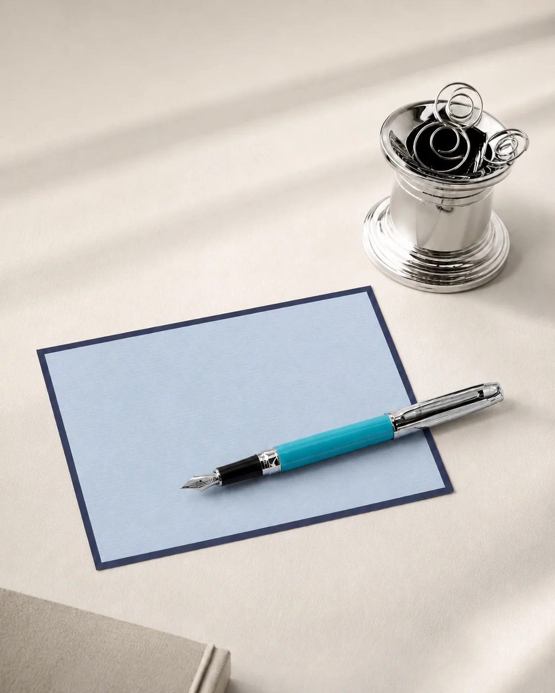Fountain pen on a blue writing card on a bright desk