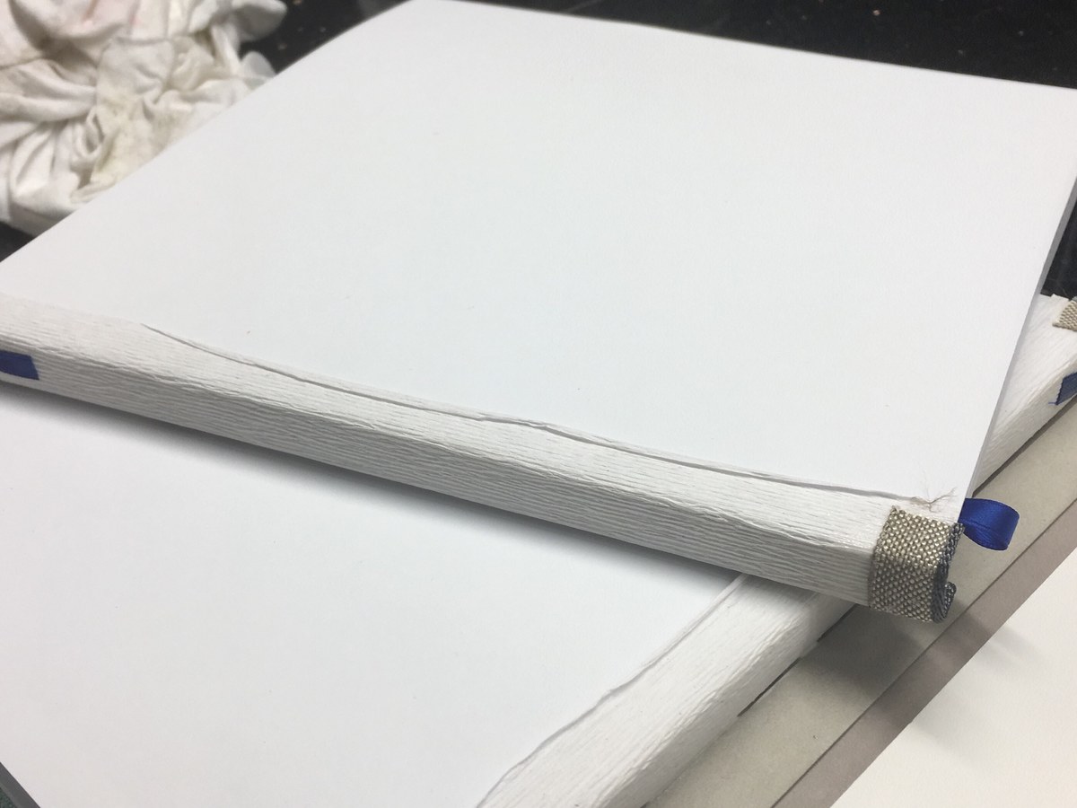Weißer Buchblock mit Klammer auf der Werkbank