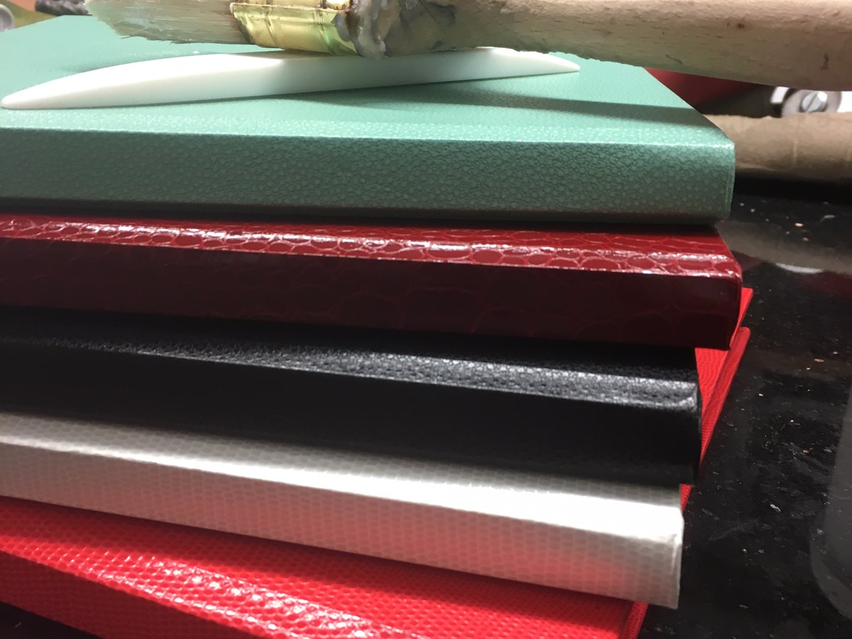 Stapel fertiger Einbände in Mint, Rot, Schwarz, Silber und Weiß