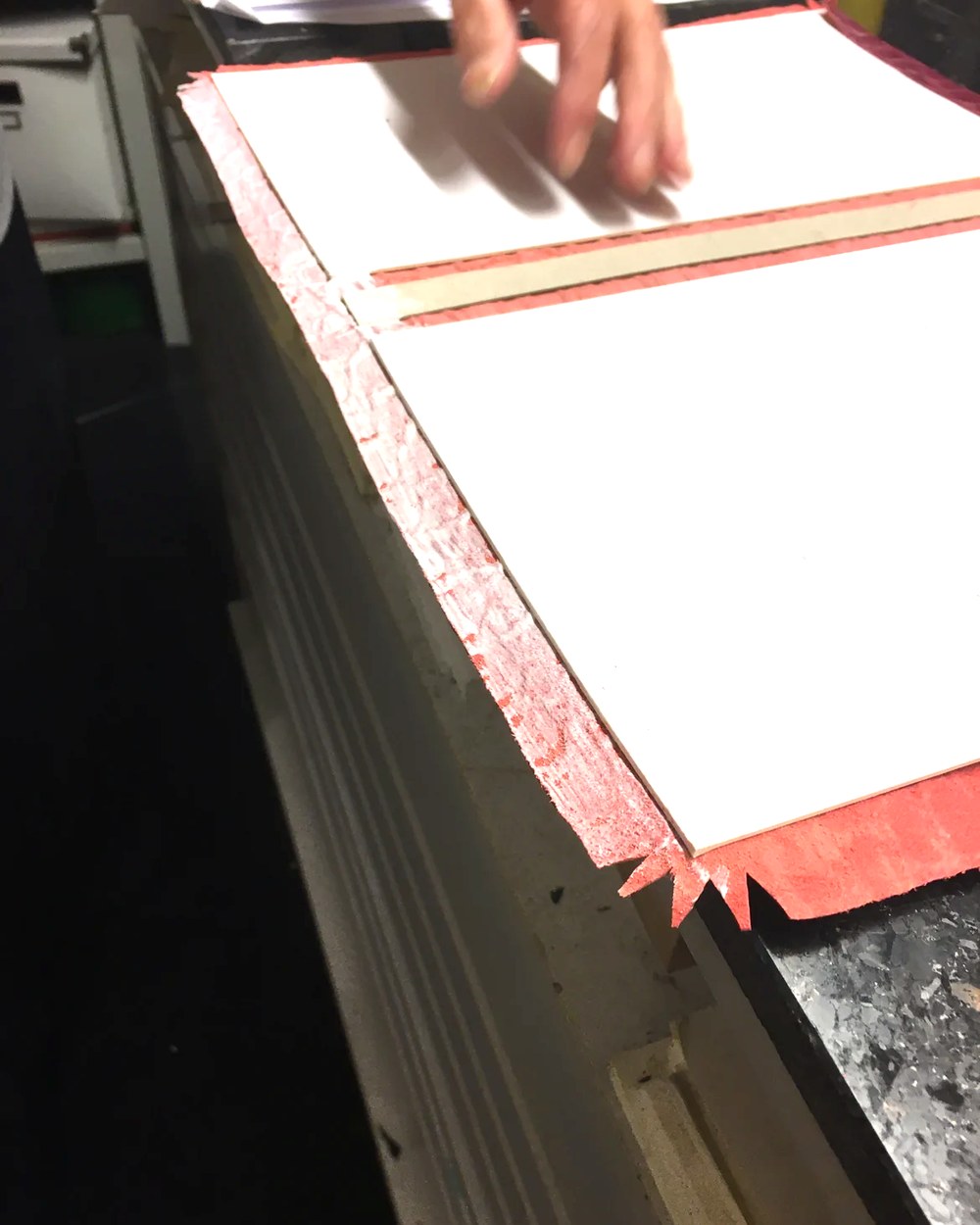 Roter Bezug wird über die Kante einer Buchdecke eingeschlagen