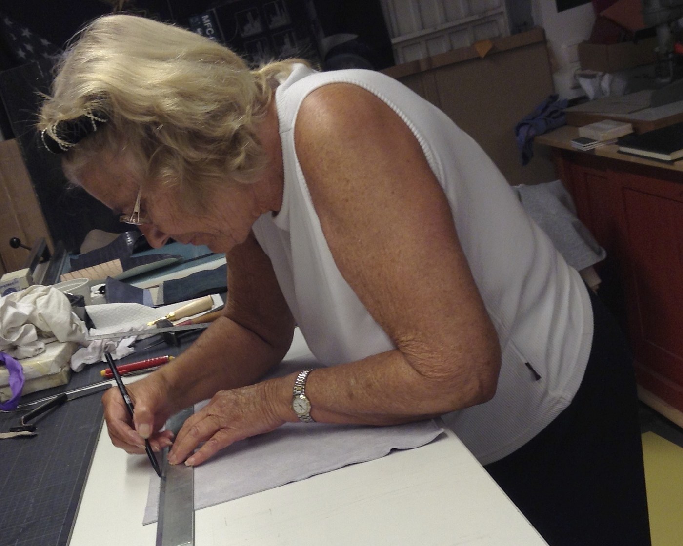 Elsbeth Gronau zeichnet mit Lineal und Bleistift an der Werkbank im Atelier an