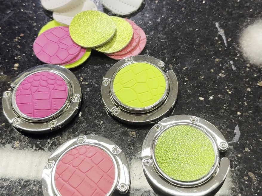 Runde Lederscheiben in Neongelb und Pink, eingesetzt in Metallfassungen