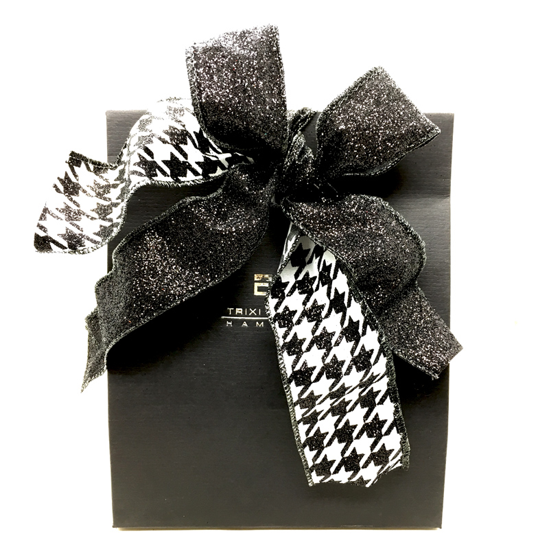 Schwarze Geschenkbox mit Hahnentrittband in Schwarz und Weiß und einer Schleife aus schwarzem Glitzerband