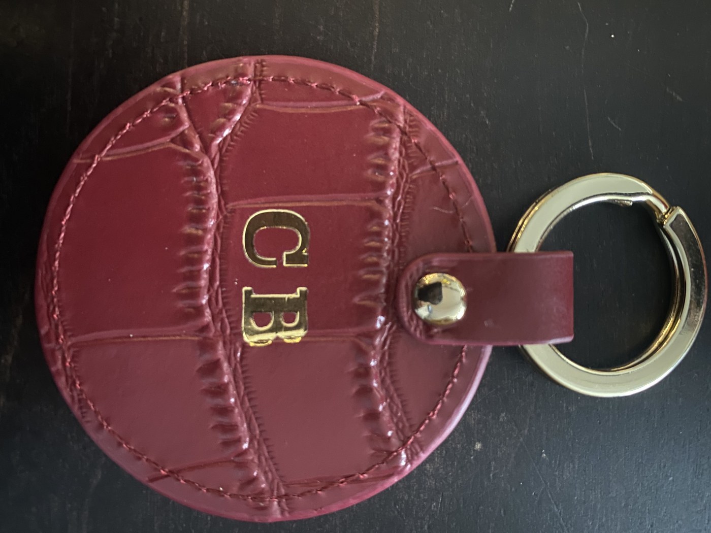 Schlüsselanhänger aus bordeauxfarbenem Leder mit goldener Prägung der Initialen