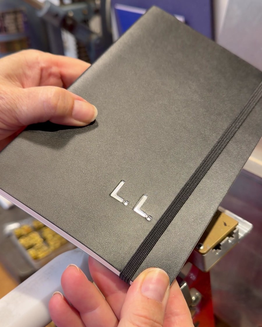 Notizbuch mit silberner Prägung der Initialen in der Hand