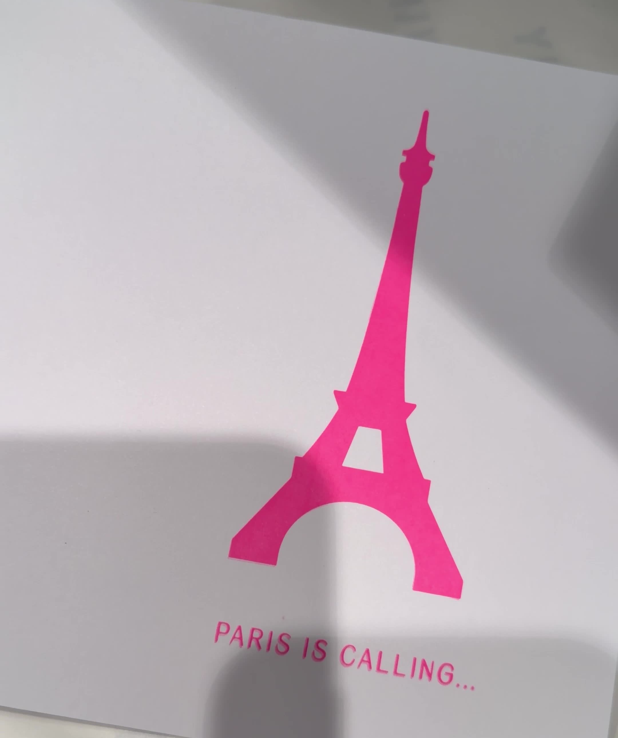 Weiße Karte mit einem Eiffelturm in Neon Pink und dem Schriftzug PARIS IS CALLING
