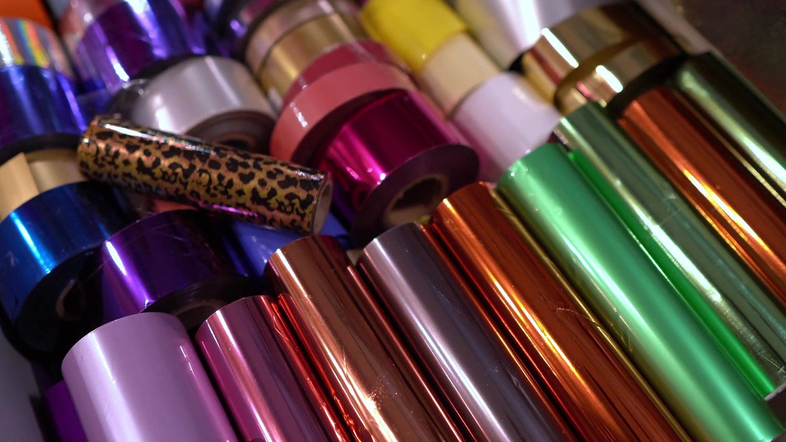 Prägefolien auf Rollen in Violett, Blau, Pink, Weiß, Gelb, Gold, Grün, Kupfer und Rosegold, dazu eine Folie mit Leopardenmuster