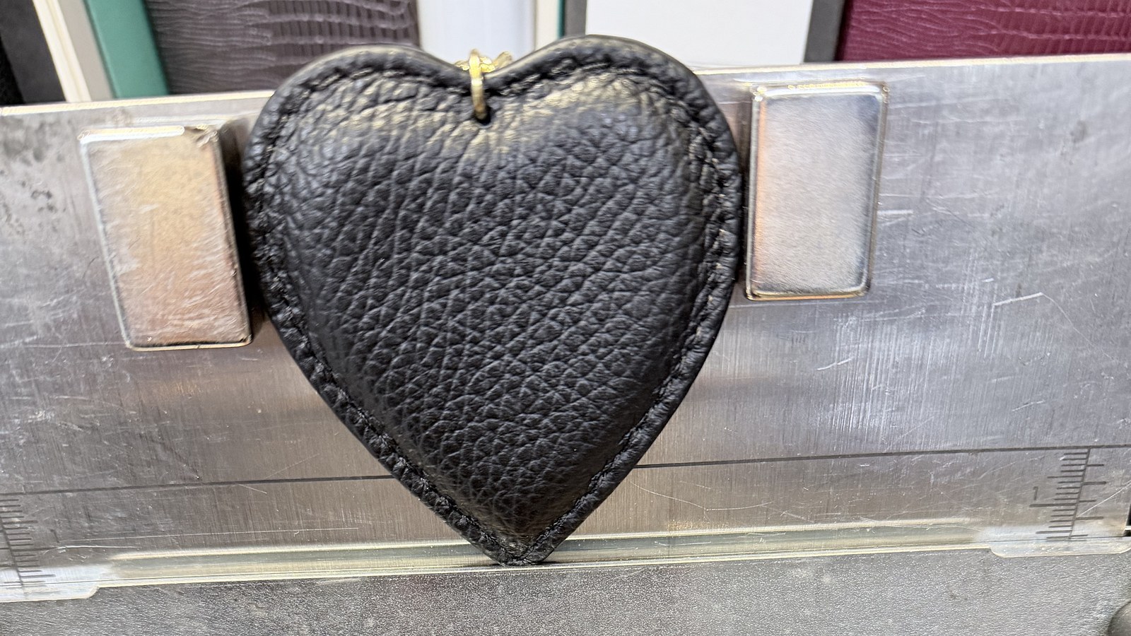 Schwarzes Lederherz zwischen zwei Anschlägen auf dem Prägebett der Maschine
