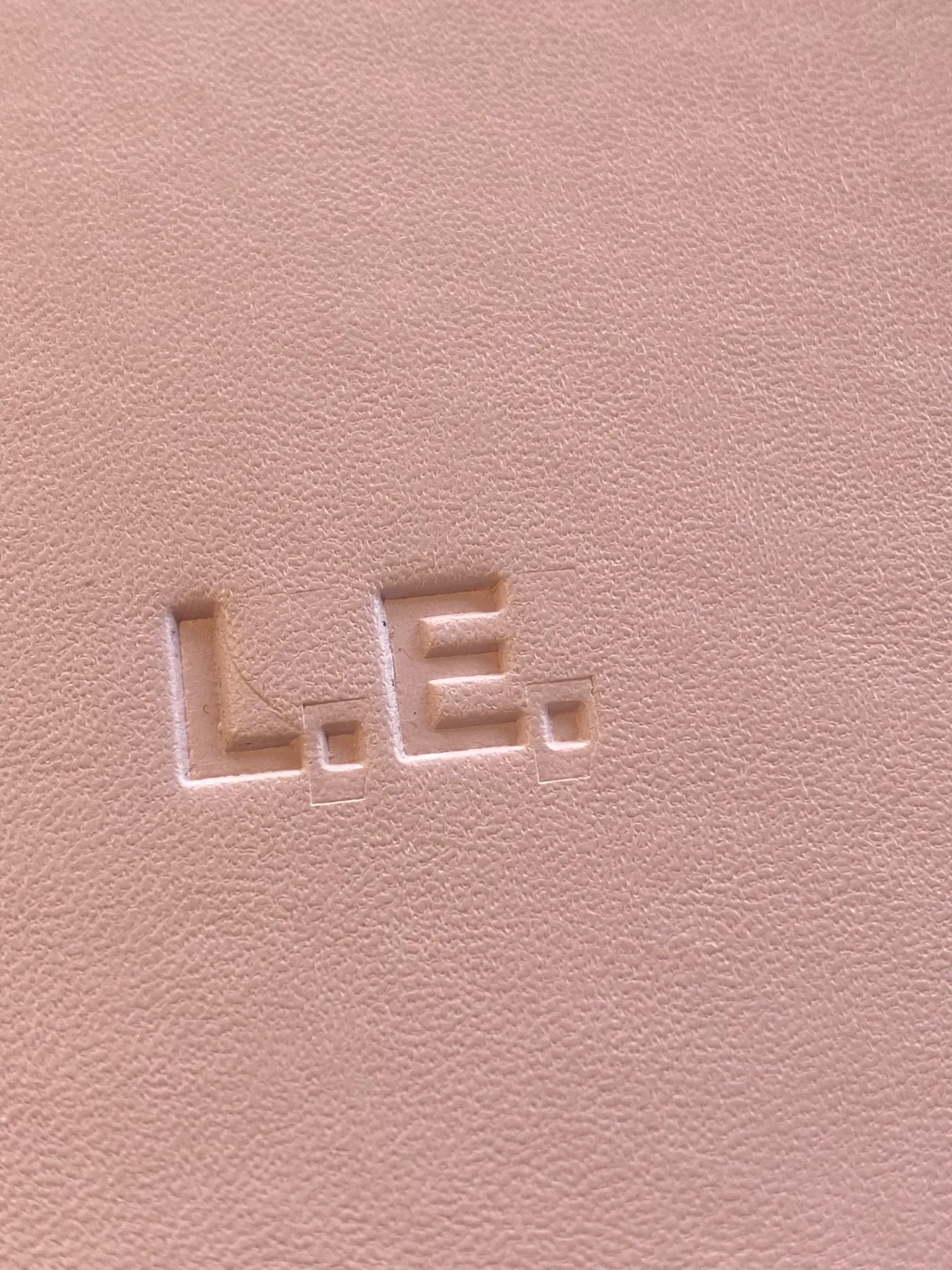 Close-up of blind embossed initials on a pink notebook
