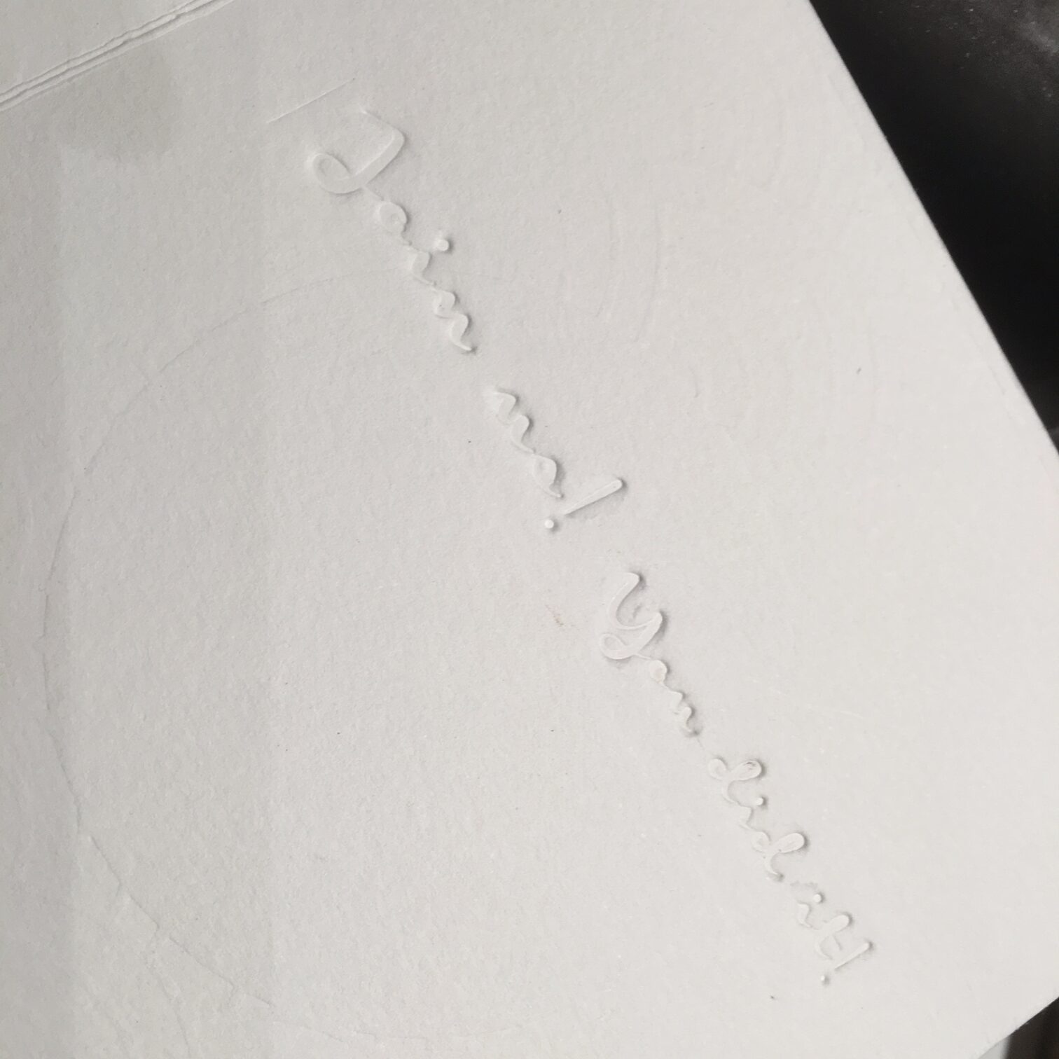 Feiner weißer Schriftzug als Blindprägung auf Papier