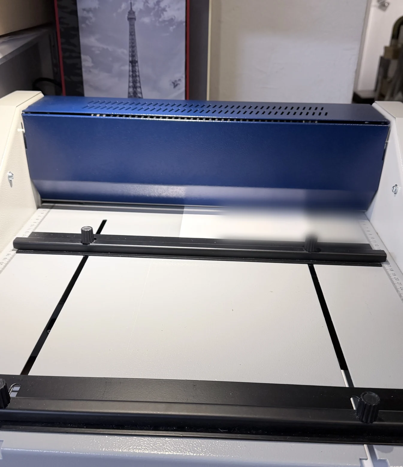 Elektrische Nutmaschine mit blauer Haube, davor der helle Arbeitstisch mit schwarzer Anlageschiene, Rändelschrauben und Zentimeterskala