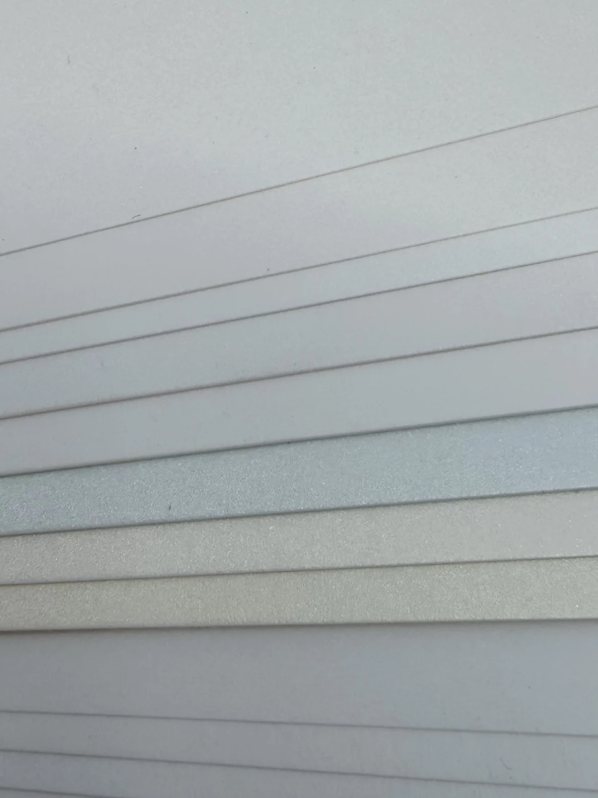 Aufgefächerte weiße Papiere mit unterschiedlichen Weißtönen und deutlich sichtbaren Papierstärken an den Kanten