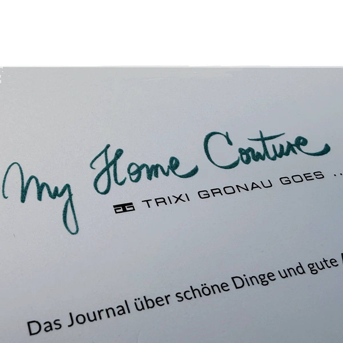 Detail of a business card with raised turquoise printing beside flat offset printing